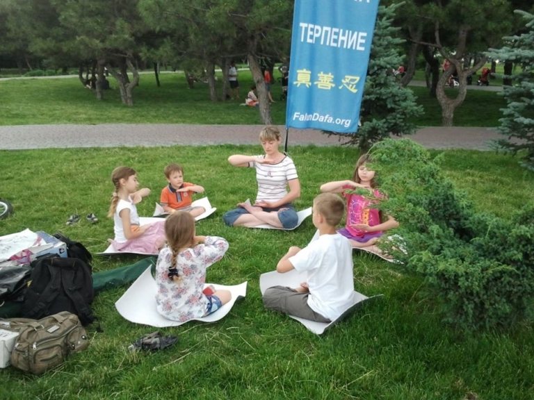 Lyudmila Orel đang luyện bài công pháp số 5 của Pháp Luân Công cùng với các em nhỏ ở công viên.